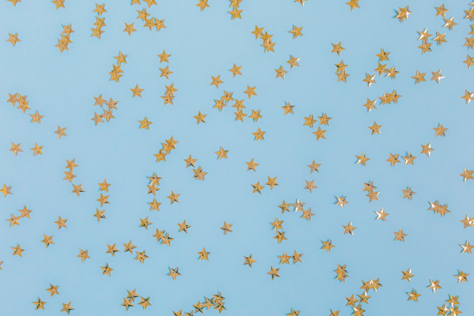 Gold star confetti scattered over a light blue surface, perfect for festive occasions
